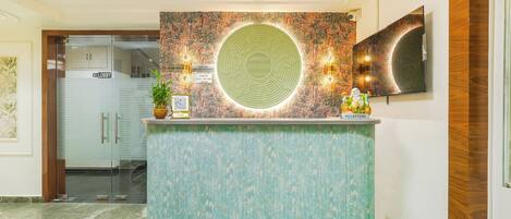A reception desk with a patterned wall, a clock, and a television.