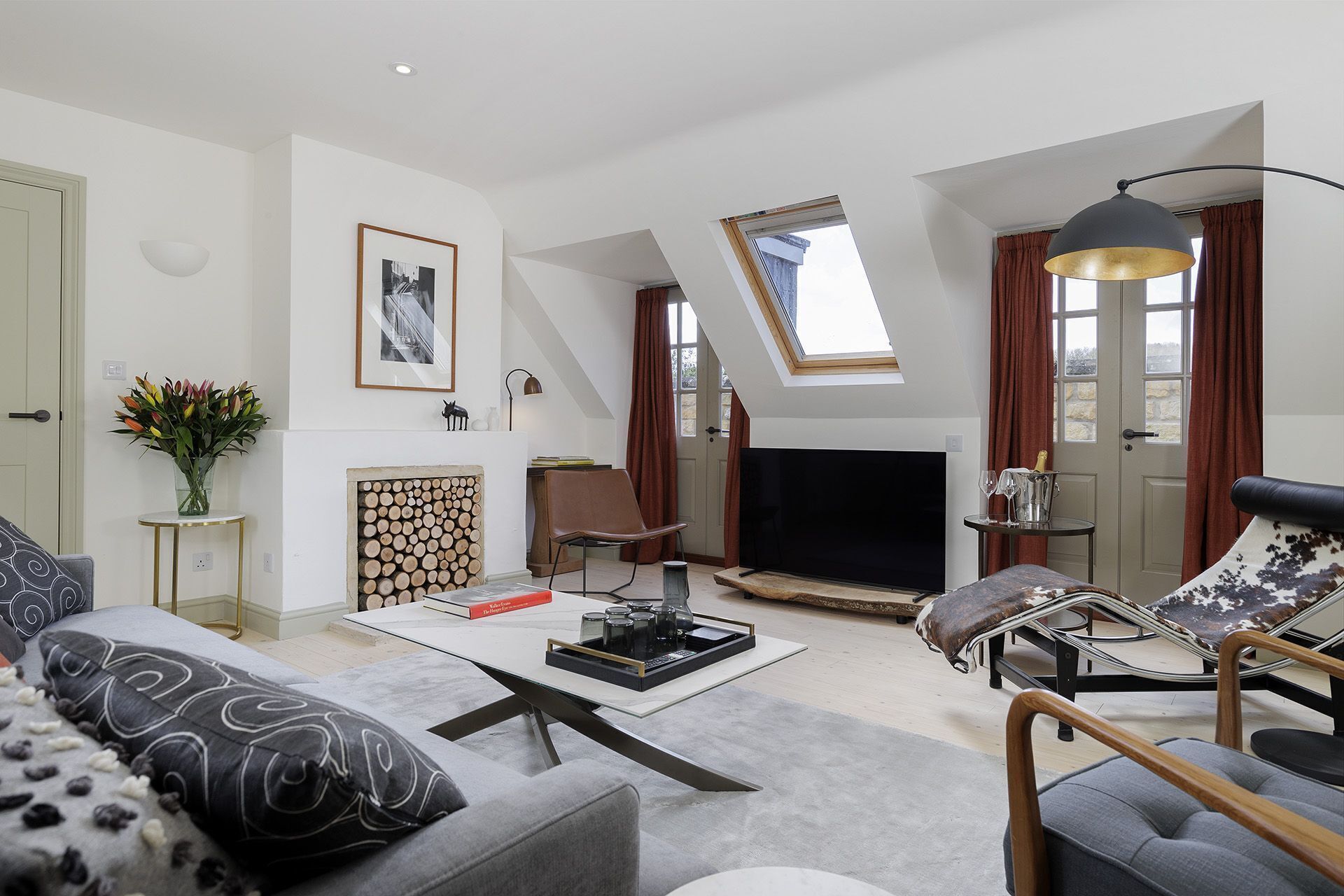 A modern living room with a flat-screen TV, a fireplace, a dining table, and a cozy seating area.