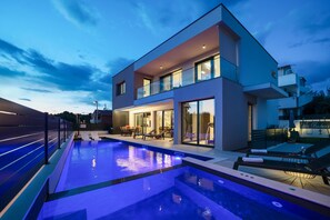 Un bâtiment moderne à deux étages doté d’une piscine, d’un espace extérieur aménagé et d’un balcon bien visible.