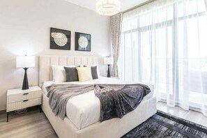 Ein modernes Schlafzimmer mit einem großen Bett, zwei Nachttischen und einer Chandelier.