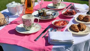 Taula a l'aire lliure amb tasses de te, plats de maduixes i pastissos.