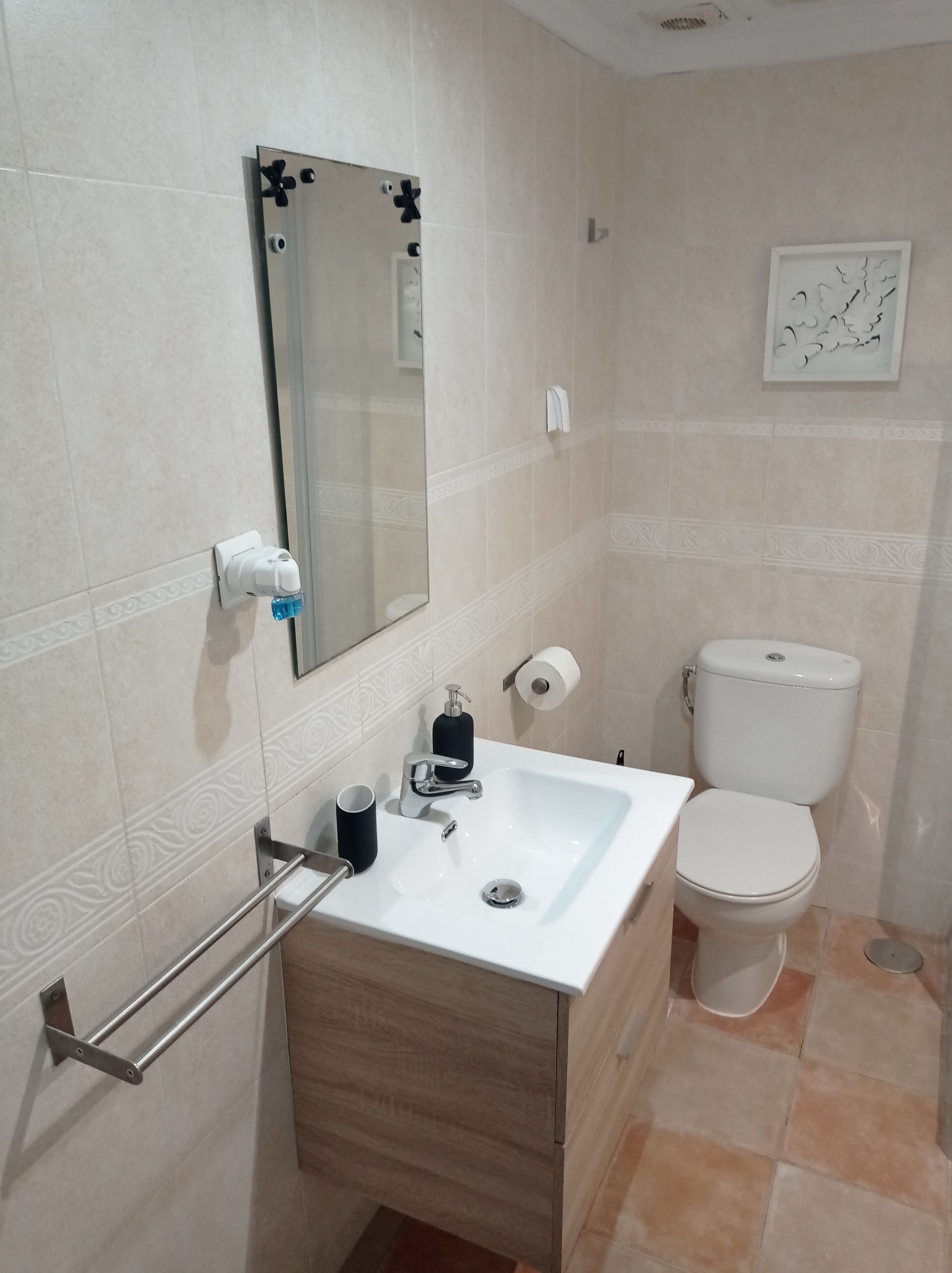 A bathroom with a white sink, a mirror, a toilet, and a towel rack.