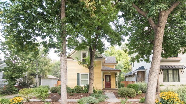 A residential house with a front yard, a pathway leading to the front door, and a small garden with yellow flowers. - Spacious Old Town Home Walk to Dining & Culture! (Fort Collins)