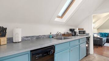 A modern kitchen with a skylight, built-in dishwasher, and a grey countertop.