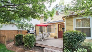 A backyard with a wooden deck, a barbecue grill, and a patio table with an umbrella. - Spacious Old Town Home Walk to Dining & Culture! (Fort Collins)