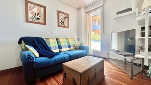 A living room with a blue sofa, a wooden chest, and a TV stand. - Island Circobueno - 5609 (Arnuero)