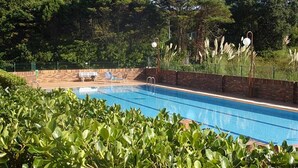 A swimming pool with a brick wall, surrounded by greenery and trees. - Island Circobueno - 5609 (Arnuero)