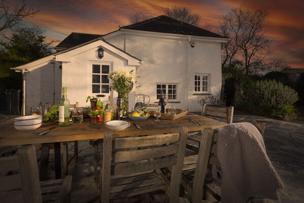 A dining table set outdoors with a white building in the background.