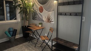 Una habitación acogedora con una mesa y sillas de madera, una planta en maceta y un letrero en la pared que dice 'welcome'.