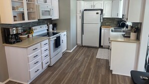 Una cocina compacta con armarios blancos, horno integrado, microondas y refrigerador.