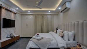 Een moderne slaapkamer met een bed, televisie, kledingkast en plafondventilator.