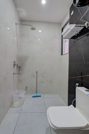 A modern bathroom with a shower, toilet, and a mop. - The Lodgers 1 BHK Apartments Sector 52 (Gurugram)
