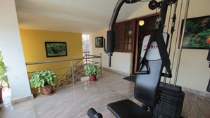 A fitness area with exercise equipment, a staircase, and potted plants. - Coorg Shell (Madikeri)