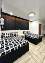 Un dormitorio moderno con dos camas, un panel de madera en la pared y una lámpara en el techo.