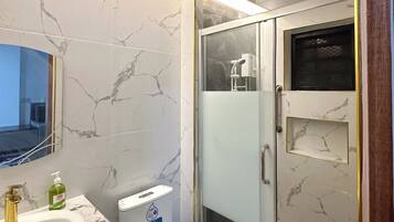 Deluxe vierpersoonskamer | Badkamer | Een douche, pantoffels, handdoeken, zeep