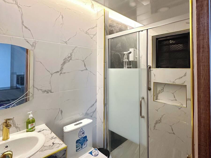 Un baño con tocador de mármol, inodoro y ducha con mampara de vidrio.