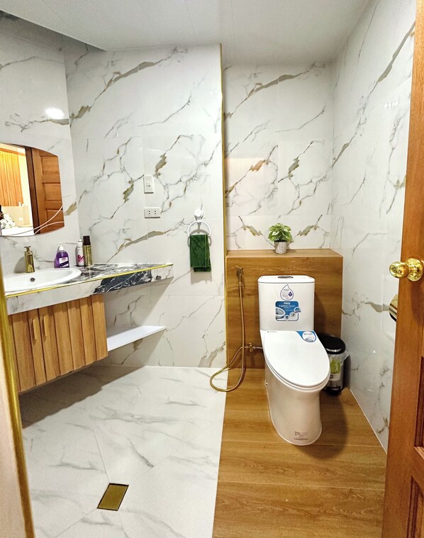 Een badkamer met een marmeren spatwand, een houten wastafelmeubel en een toilet met een bidet.