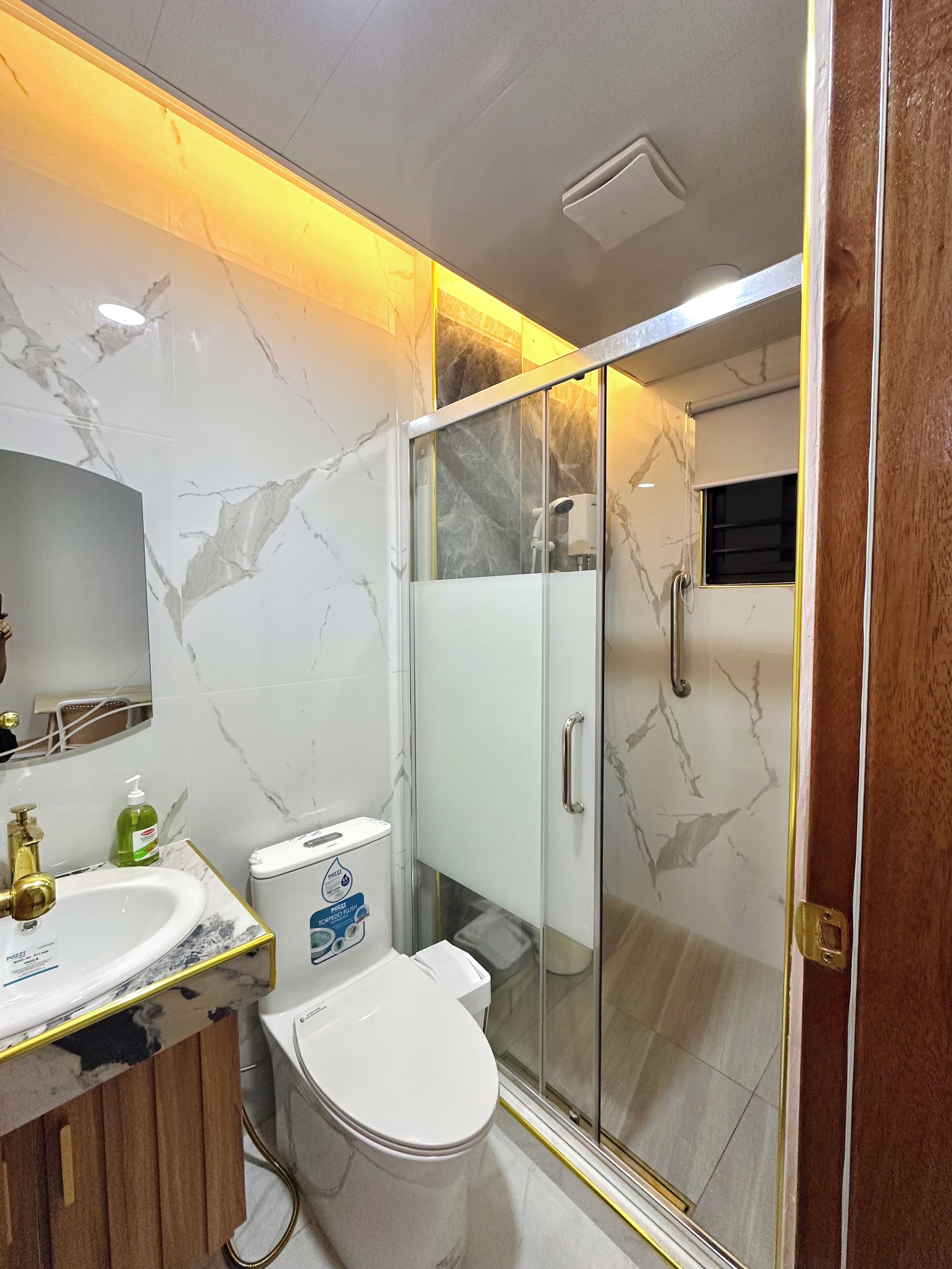 Une salle de bain moderne avec un meuble-lavabo en marbre, des toilettes et une douche à parois de verre.