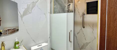Une salle de bain moderne avec un meuble-lavabo en marbre, des toilettes et une douche à parois de verre.