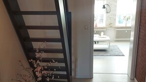 A spacious hallway with a wooden staircase leading to an outdoor area. - Quiet and centrally located apartment (approx. 80m/2) Friedeburg "The gateway to the North Sea" (Friedeburg)