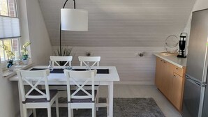 A compact kitchen with a dining table and chairs, a modern light fixture, and a refrigerator. - Quiet and centrally located apartment (approx. 80m/2) Friedeburg "The gateway to the North Sea" (Friedeburg)