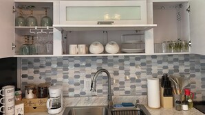 A modern kitchen with white cabinets, a stainless steel sink, and a hexagonal tile backsplash.