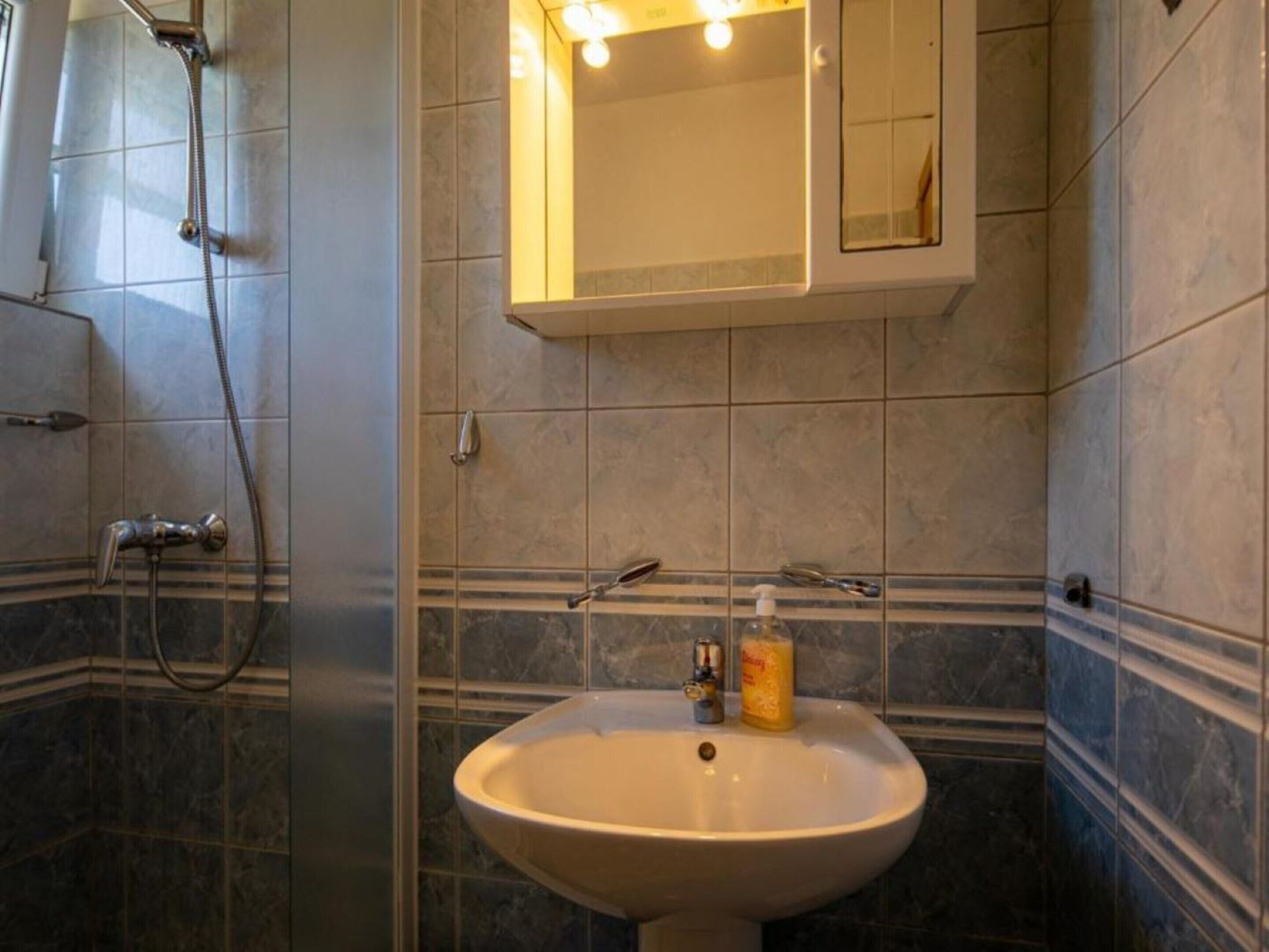 Ein Badezimmer mit Waschbecken, Spiegel und Dusche.