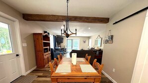 A dining area with a wooden table, chairs, and a chandelier. - Peninsula Perch: Water & Trails (Wiarton)