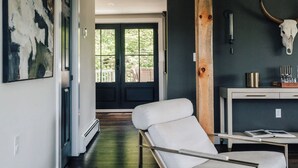 Un intérieur moderne avec une chaise blanche, un grand tableau abstrait et un crâne de vache accroché au mur.
