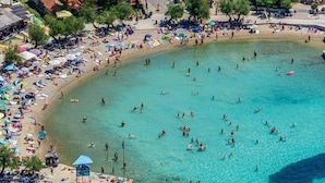 Egy tengerparti terület, ahol van egy strand, tiszta víz, és egy hajó a partra van kötve.