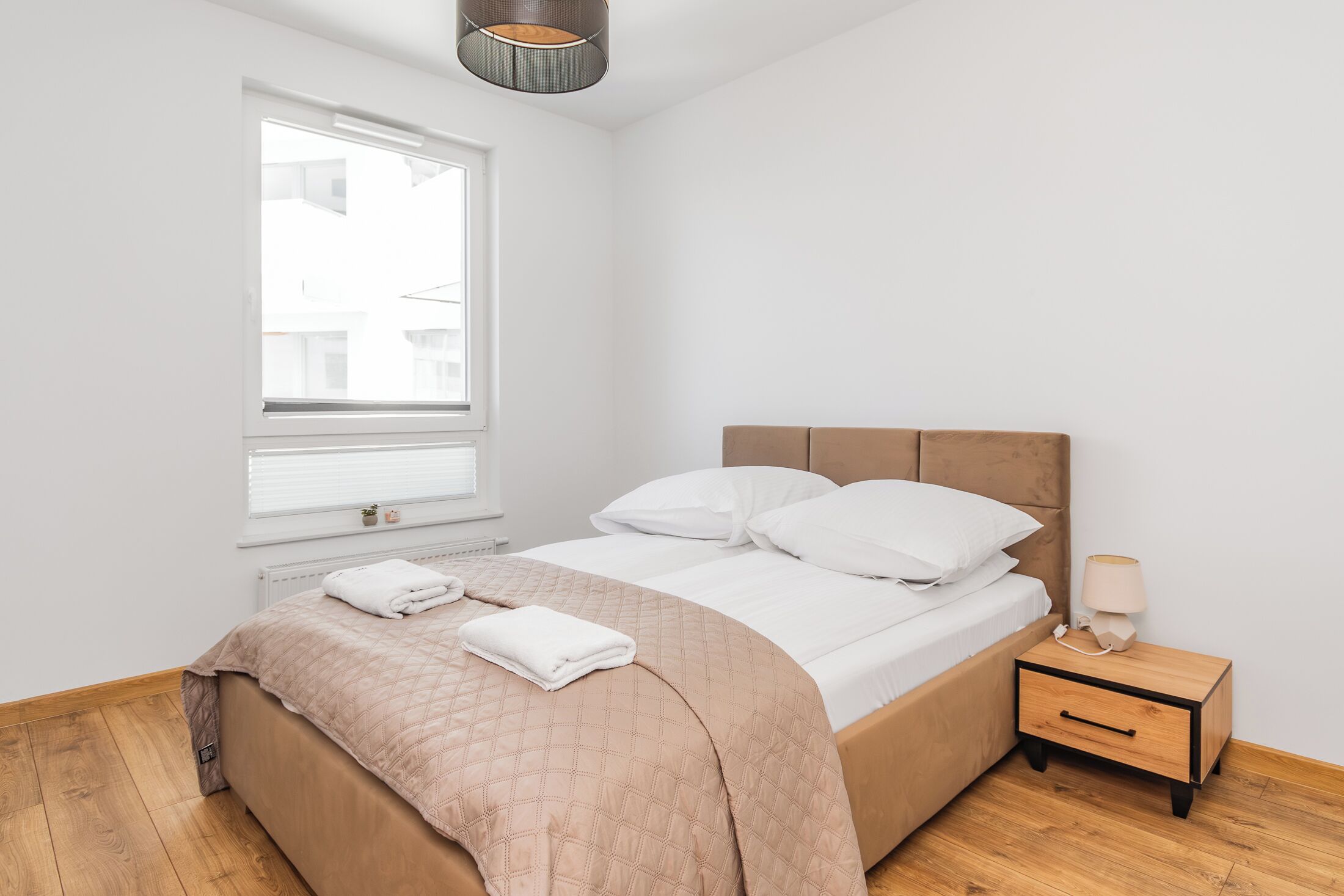 A bedroom with a bed, bedside table, and a window.