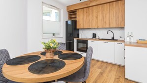 Une cuisine moderne avec des meubles en bois, un réfrigérateur noir et un pare-feu en marbre.