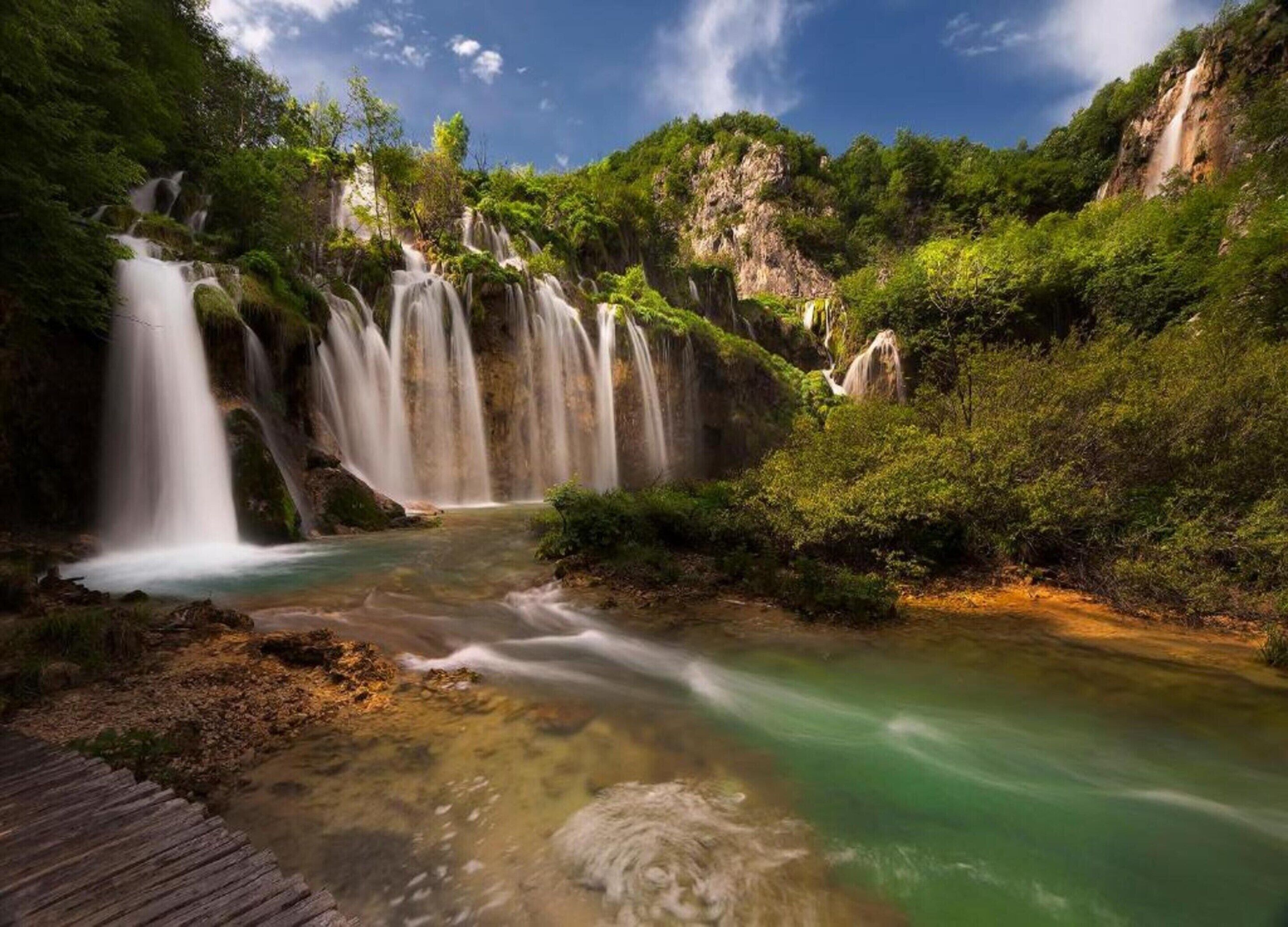 A waterfall with multiple cascades surrounded by lush greenery.