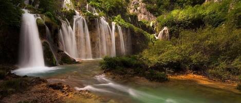 A waterfall with multiple cascades surrounded by lush greenery.