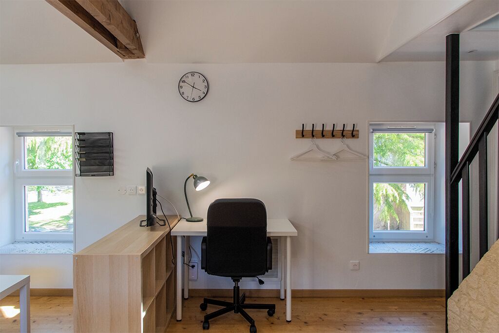 A room with a desk, chair, and a clock on the wall.