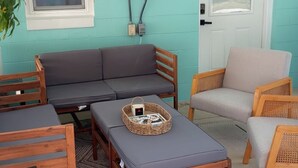 Un espace patio accueillant avec une table en bois, deux fauteuils rembourrés, un canapé et un petit tapis.
