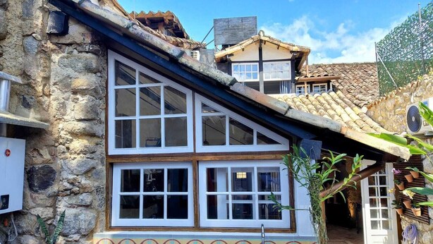 Un bâtiment en pierre avec un toit en tuiles, de grandes fenêtres et un évier blanc.