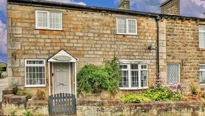 A stone cottage with a sign reading "CLOGGERS COTTAGE".