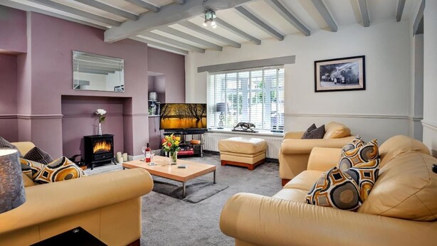 A living room with a fireplace, leather sofas, a coffee table, and a large window with blinds.
