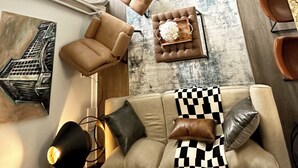 Un salon moderne comprenant un canapé, des fauteuils, une table basse et un coin repas avec une table et des chaises.