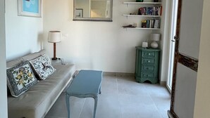 Una sala de estar con un sofá, una mesita, un espejo y una estantería.