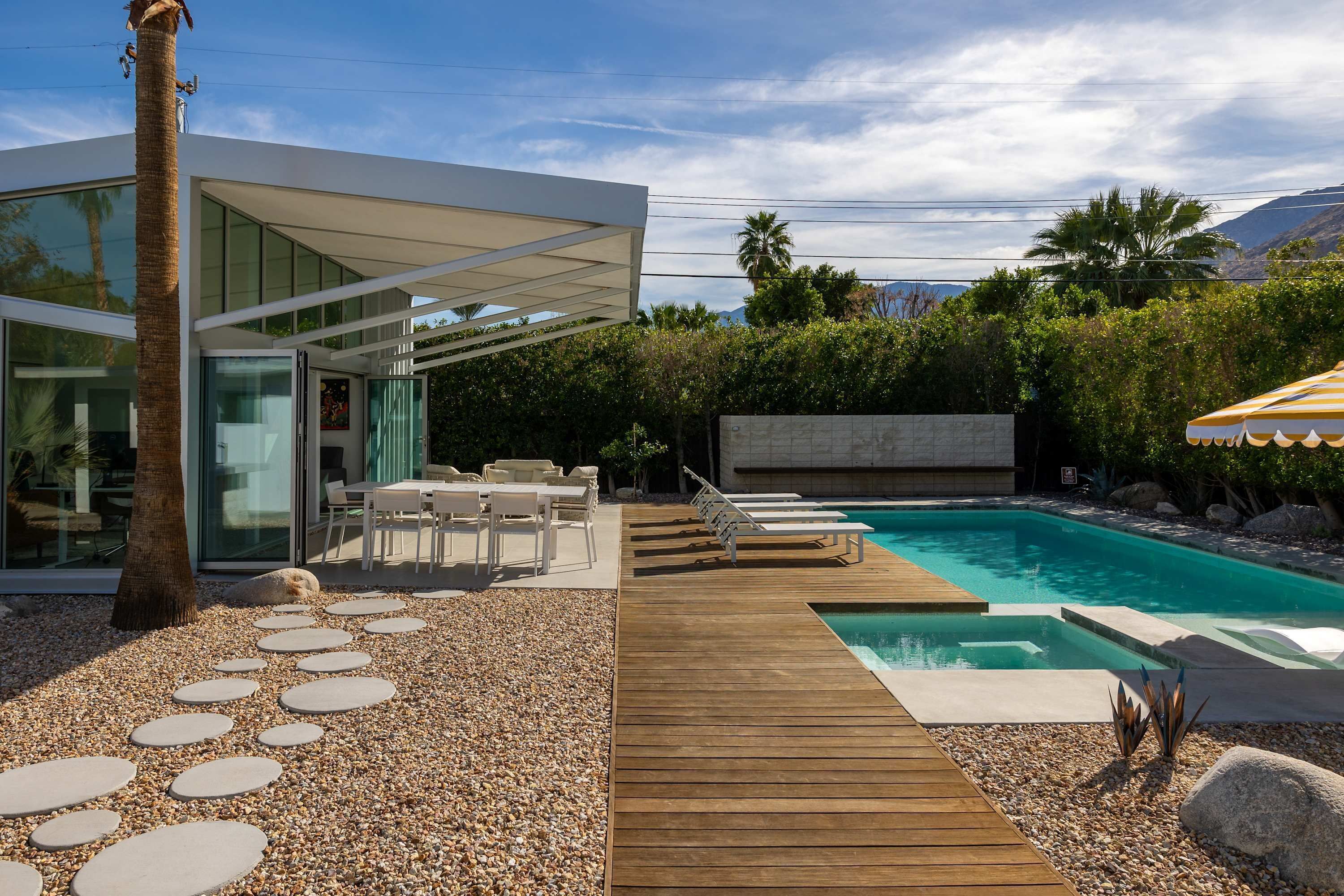 Una casa moderna con piscina, mobiliario de exterior y terraza de madera.