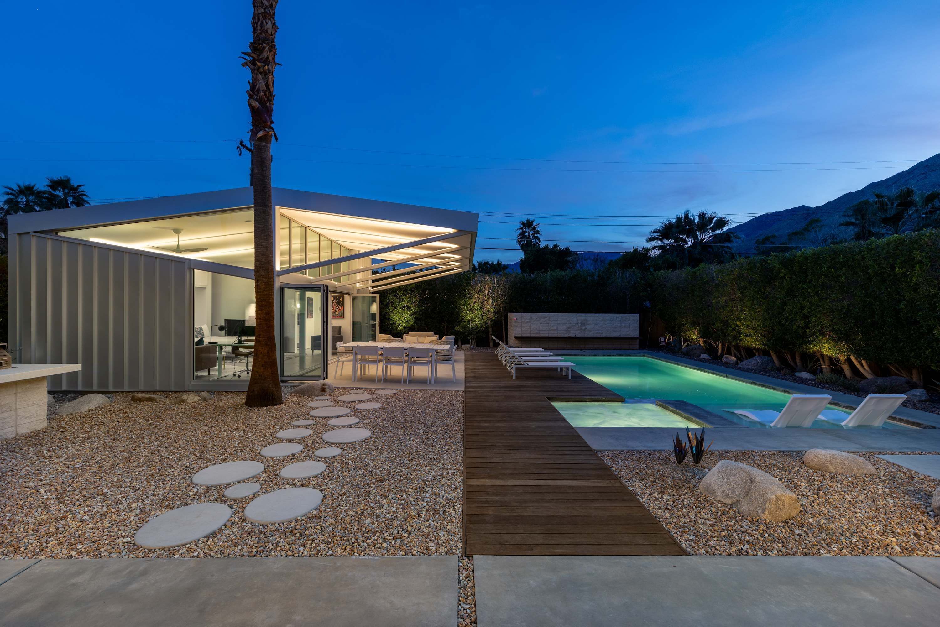 Moderni talo, jossa on uima-allas, ulkotila istuimineen ja puinen terassi.