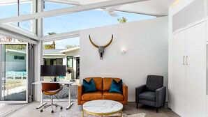 A modern living room with a glass ceiling, a large window, a sofa with blue cushions, a coffee table, and a wall-mounted bull's head sculpture. - Luxury 4-bedroom Home With Pool Spa Stunning Mountain Views (Palm Springs)