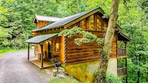 A wooden cabin with a porch, a small deck, and a stone pathway leading to the entrance. - Hunter Hills Haven - Secluded Luxe Cabin Getaway With Mountain Views Spa Hot Tub Game Room (Sevierville)