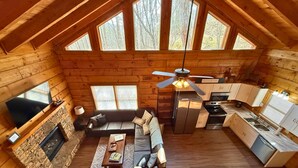 A spacious cabin with a living area, kitchen, and a fireplace. - Hunter Hills Haven - Secluded Luxe Cabin Getaway With Mountain Views Spa Hot Tub Game Room (Sevierville)