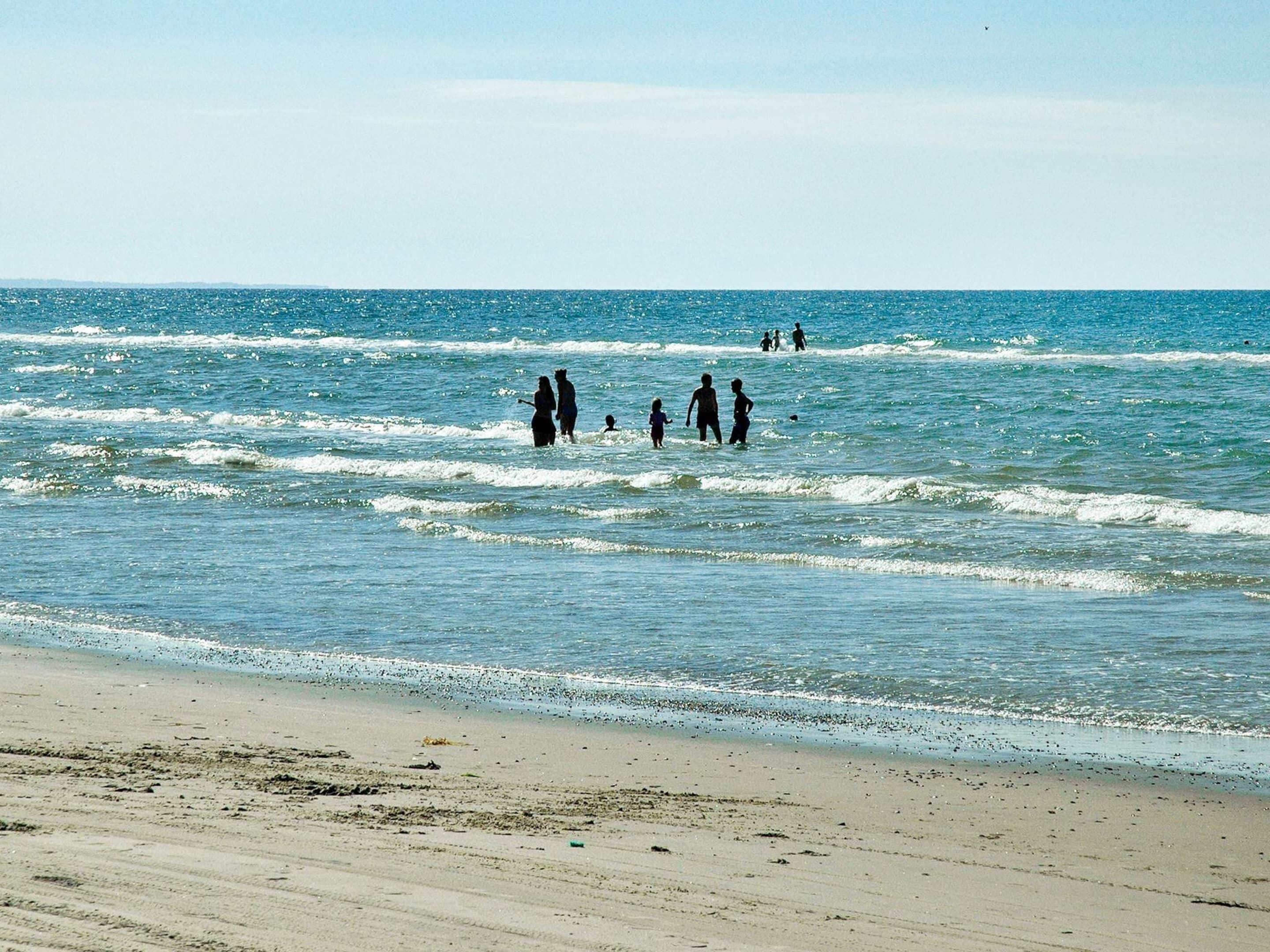 Ein Strand mit Menschen, die im Wasser und im Sand spazieren gehen.