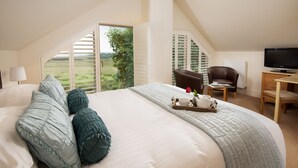 A bedroom with a large bed, a TV, a desk, and a view of a green landscape. - Two self catering holiday homes that sleeps 14 guests  in 7 bedrooms (Hexham)