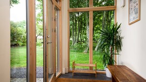 A room with a bench, a potted plant, and a large window overlooking a garden. - Two self catering holiday homes that sleeps 14 guests  in 7 bedrooms (Hexham)
