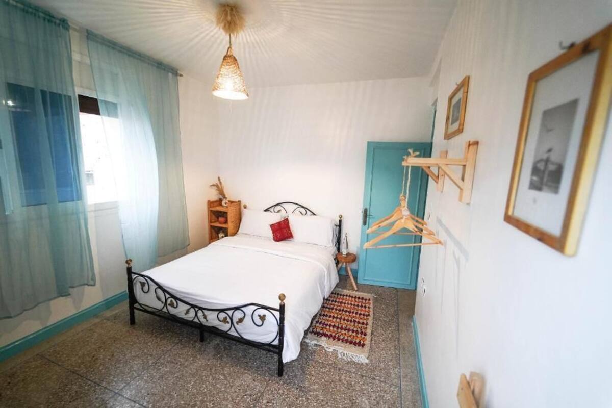 A bedroom with a bed, a hanging light fixture, a wardrobe, and wall-mounted pictures.